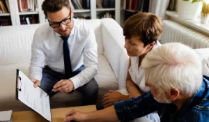 Advisor explaining pre-acquisition surveys report on clipboard to senior couple at home