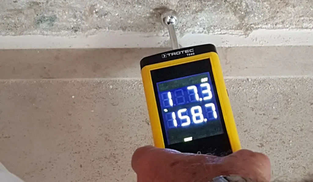 RICS homebuyers report inspection, a surveyor moisture meter taking a reading on a wall